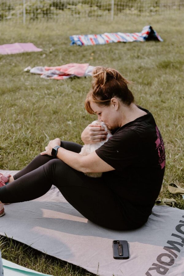 Woman cuddling a Goldendoodle puppy during a yoga session at Deer Creek Doodles.