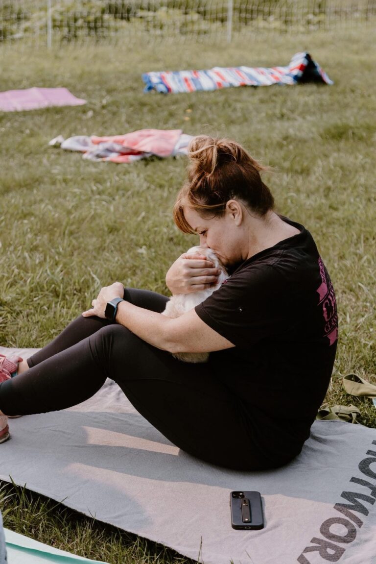 Woman cuddling a Goldendoodle puppy during a yoga session at Deer Creek Doodles.