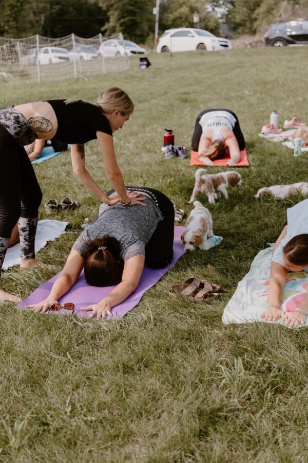 Woman sitting cross-legged, holding a Goldendoodle puppy close during a relaxing yoga session.